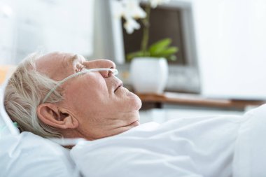 side view of senior man in coma on bed in hospital clipart