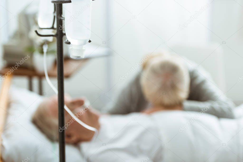 selective focus of sad senior woman with husband in coma in clinic