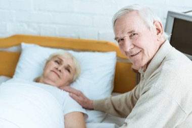klinikte hasta karısı ile gülümseyen kıdemli adam