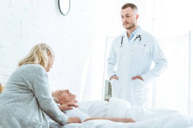 klinikte hasta ve kıdemli kadın yakın pockers elleri ile ayakta ciddi doktor