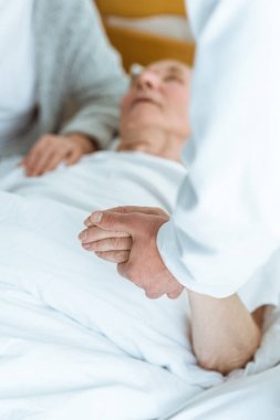 komada hastanın yanında duran ve elini tutan doktor kırpılmış görünümü