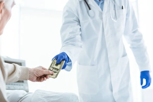 病院の部屋で医師に賄賂を与える高齢者の部分的な見解 — ストック写真
