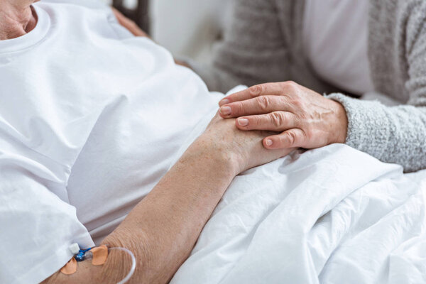 частичный взгляд пожилой женщины с больным мужем в клинике
