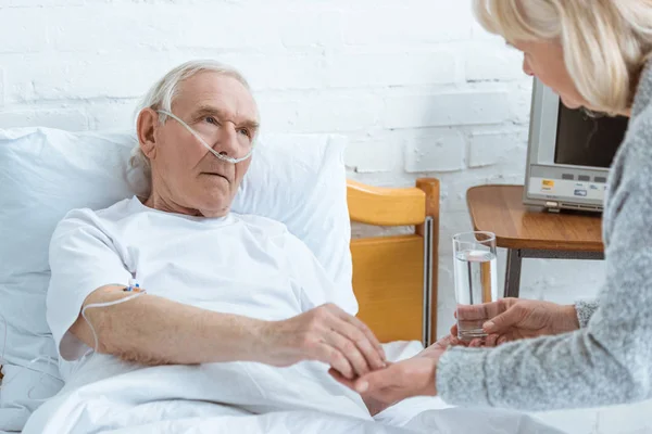 Cropped View Senior Woman Giving Glass Water Sick Husband Hospital — Stock Photo, Image