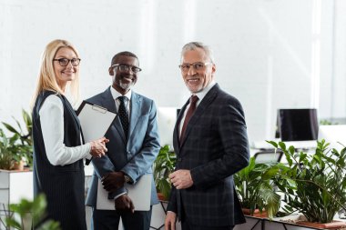 neşeli işadamları ve iş kadını ofiste ayakta seçici odak 