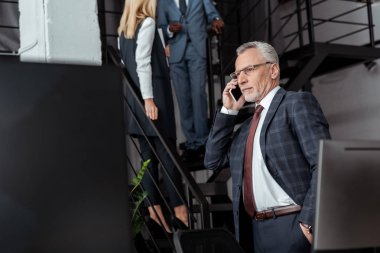 çok kültürlü iş ortaklarının yanında akıllı telefon konuşan işadamı seçici odak 