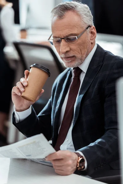 Guapo Hombre Negocios Mirando Periódico Mientras Sostiene Taza Desechable —  Fotos de Stock