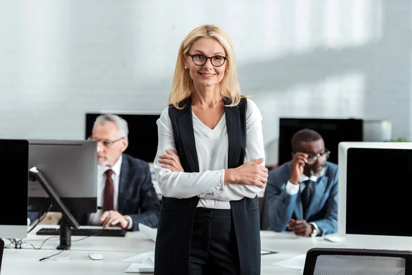 Selective Focus Cheerful Businesswoman Standing Crossed Arms Multicultural Men Office — Stock Photo, Image