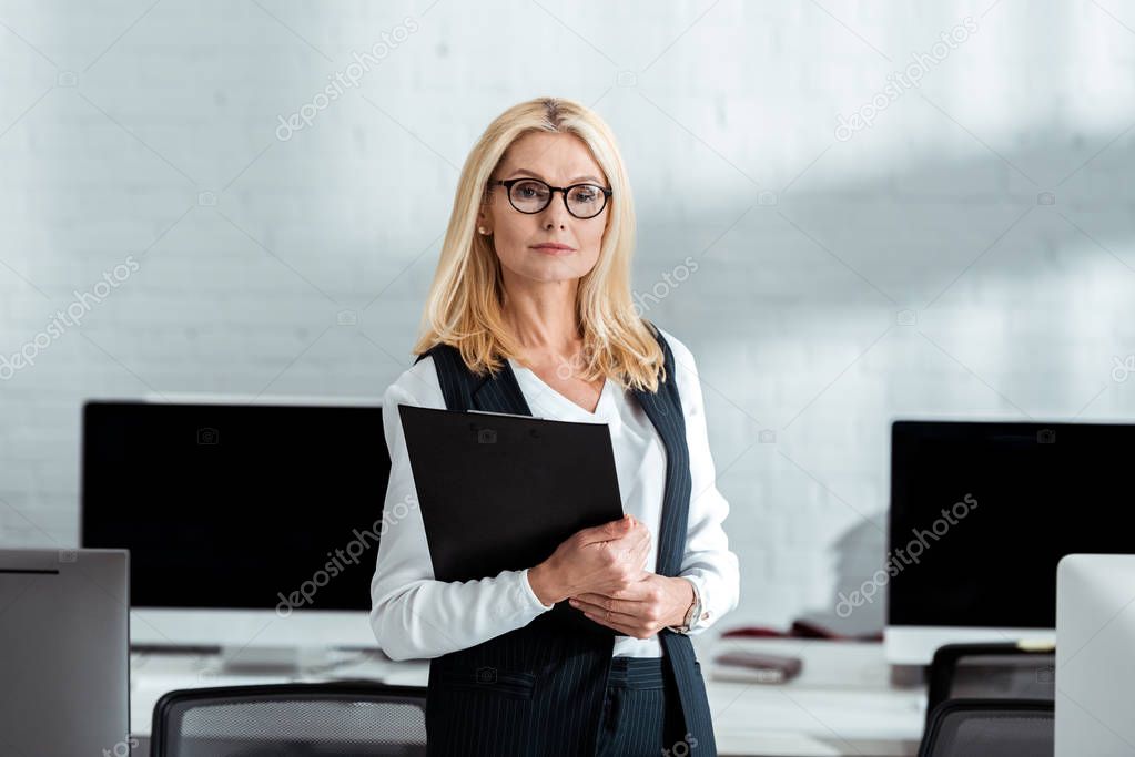 attractive blonde businesswoman in glasses holding clipboard in hands 