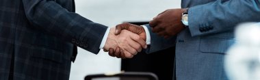 panoramic shot of african american businessman shaking hands with partner  clipart