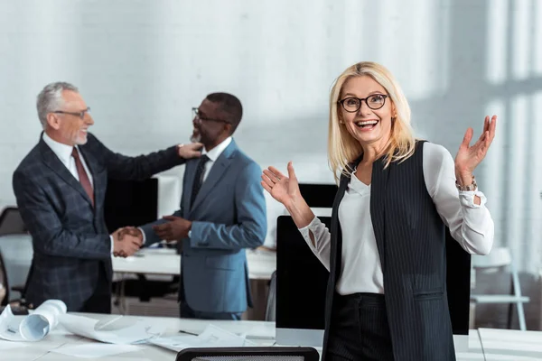 Selective Focus Happy Businesswoman Gesturing Multicultural Businessmen Shaking Hands Office — Stock Photo, Image