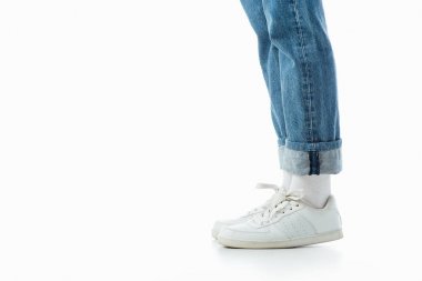 cropped view of teenage girl legs in white sneakers and blue jeans isolated on white clipart