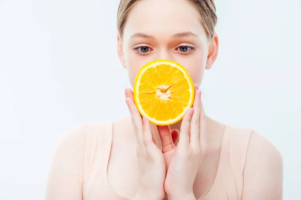 白で隔離された口の前で熟したオレンジ色の半分を保持する十代の少女 — ストック写真