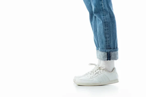 白いスニーカーと青いジーンズの十代の女の子の足のトリミングビューは 白で隔離 — ストック写真