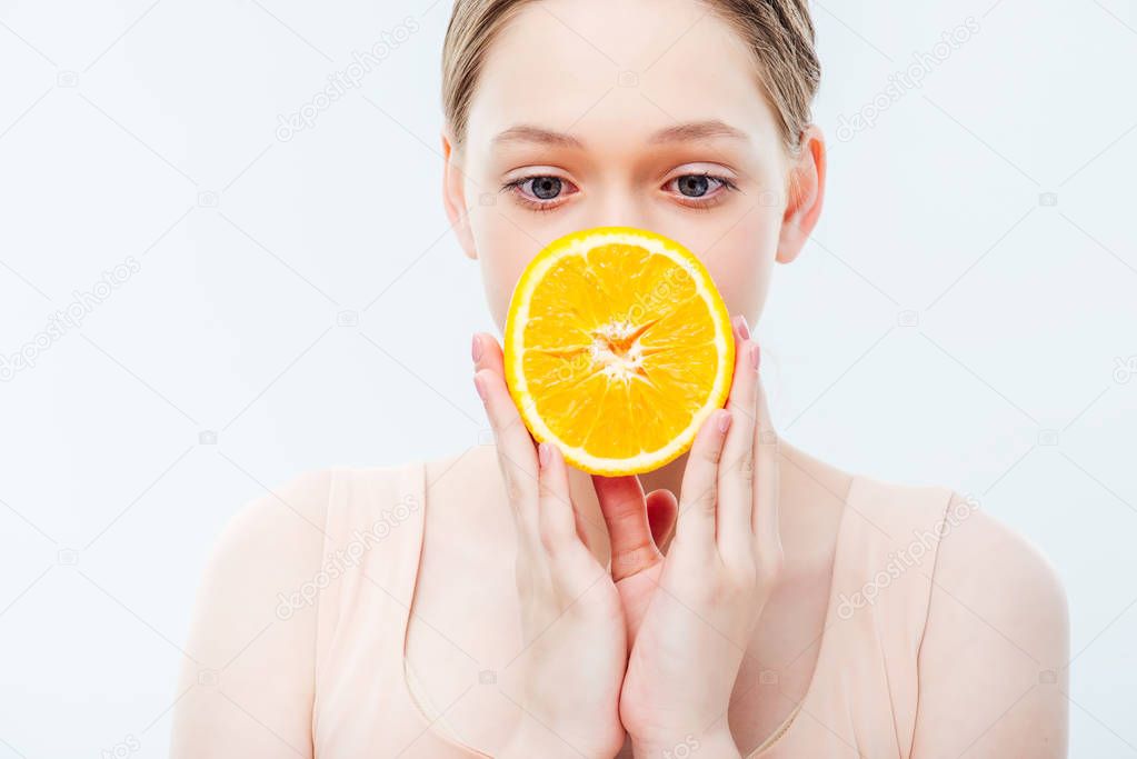 teenage girl holding ripe orange half in front of mouth isolated on white