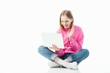Beyaz, açıklayıcı editoryal üzerinde izole video sohbet sırasında laptop ekranında el sallayarak mutlu gülümseyen genç kız