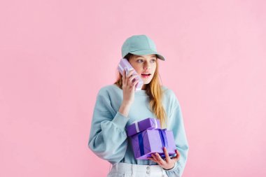 pembe üzerinde izole telefon olarak Cap Holding mevcut güzel genç kız sürpriz