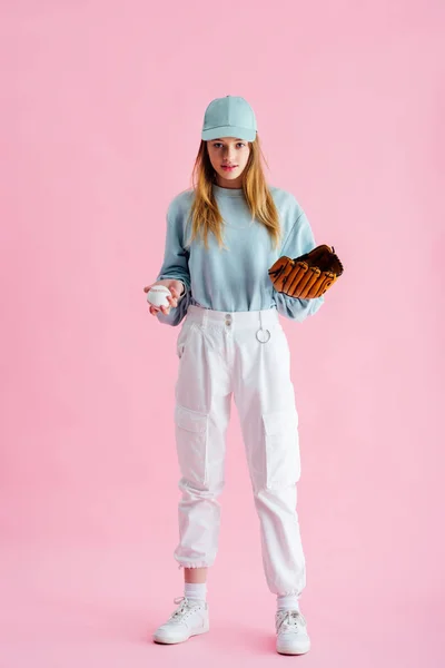 漂亮的十几岁的女孩在帽子拿着棒球手套和球在粉红色 — 图库照片