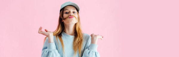 Панорамный снимок красивой девушки-подростка в шапке с усами из волос гримасы изолированы на розовый
