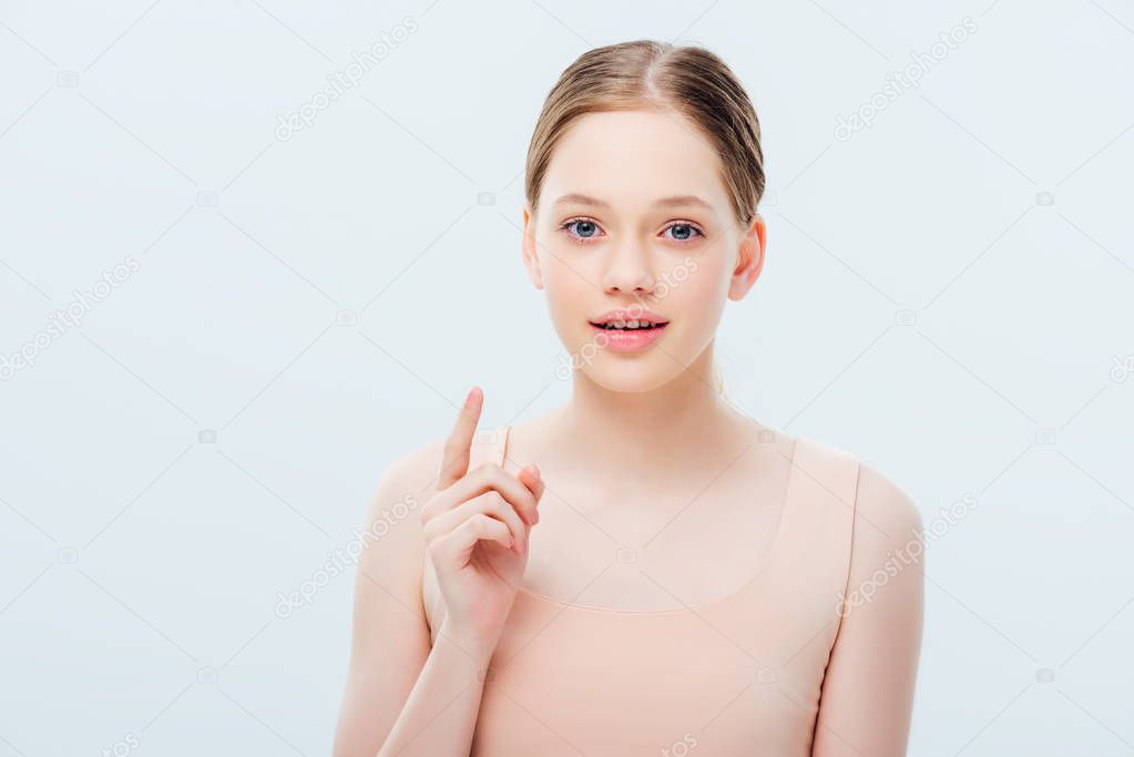 pretty teenage girl looking at camera and showing idea gesture isolated on grey