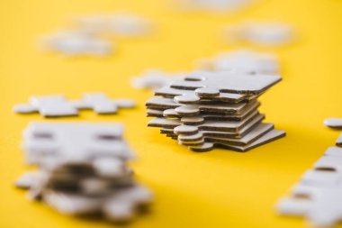selective focus of stacked white puzzle pieces on yellow  clipart