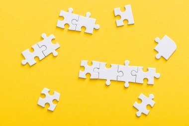 top view of connected jigsaw puzzle pieces isolated on yellow  clipart
