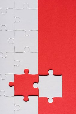 top view of incomplete jigsaw near white puzzle piece isolated on red clipart
