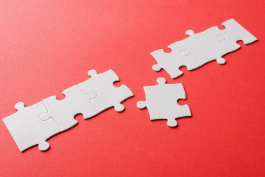 white connected jigsaw near puzzle piece on red  clipart