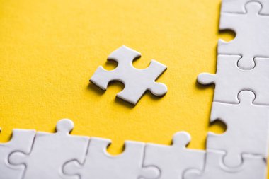 white puzzle piece near connected jigsaw on yellow  clipart