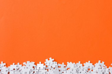 top view of incomplete puzzle pieces isolated on orange with copy space clipart