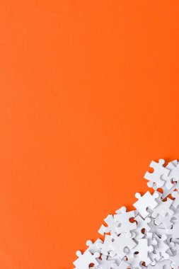 top view of unfinished puzzle pieces isolated on orange with copy space clipart