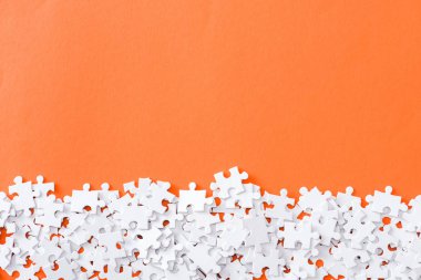 top view of unfinished white puzzle pieces isolated on orange with copy space clipart