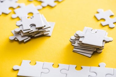 selective focus of connected and unfinished puzzle pieces on yellow  clipart