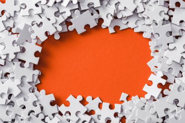 top view of frame of white jigsaw puzzle pieces on orange clipart