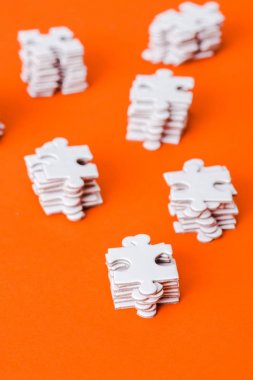 selective focus of stacks with white puzzle pieces on orange clipart