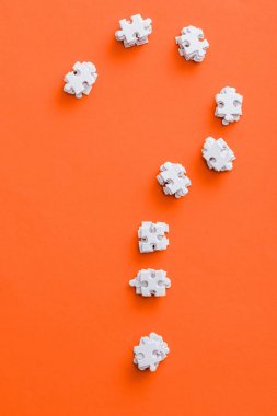  top view of question mark shape with white puzzle pieces on orange clipart