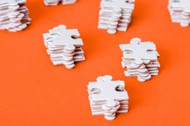 selective focus of white jigsaw puzzle pieces stacks on orange clipart