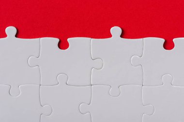 top view of matched white jigsaw puzzle pieces isolated on red  clipart