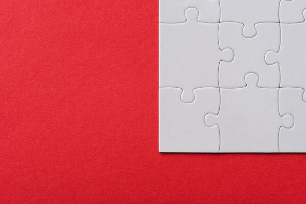 top view of connected white jigsaw puzzle pieces isolated on red 