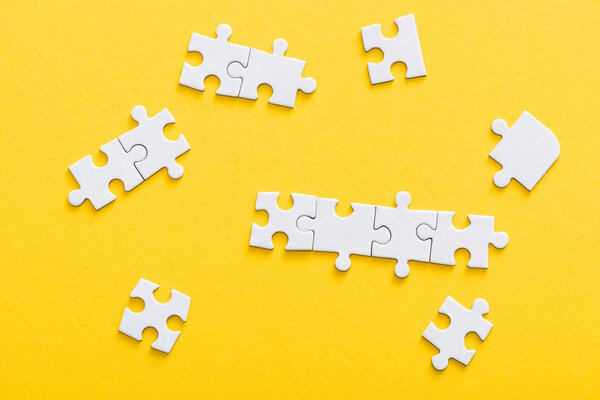 top view of connected jigsaw puzzle pieces isolated on yellow 