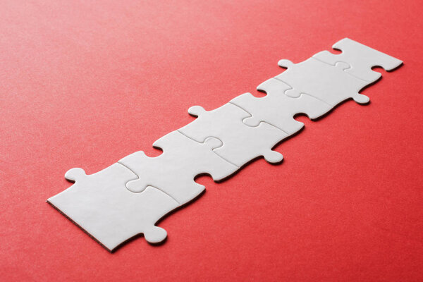 white line of connected jigsaw puzzle pieces on red 