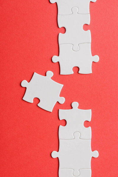 top view of white connected jigsaw near puzzle piece isolated on red 