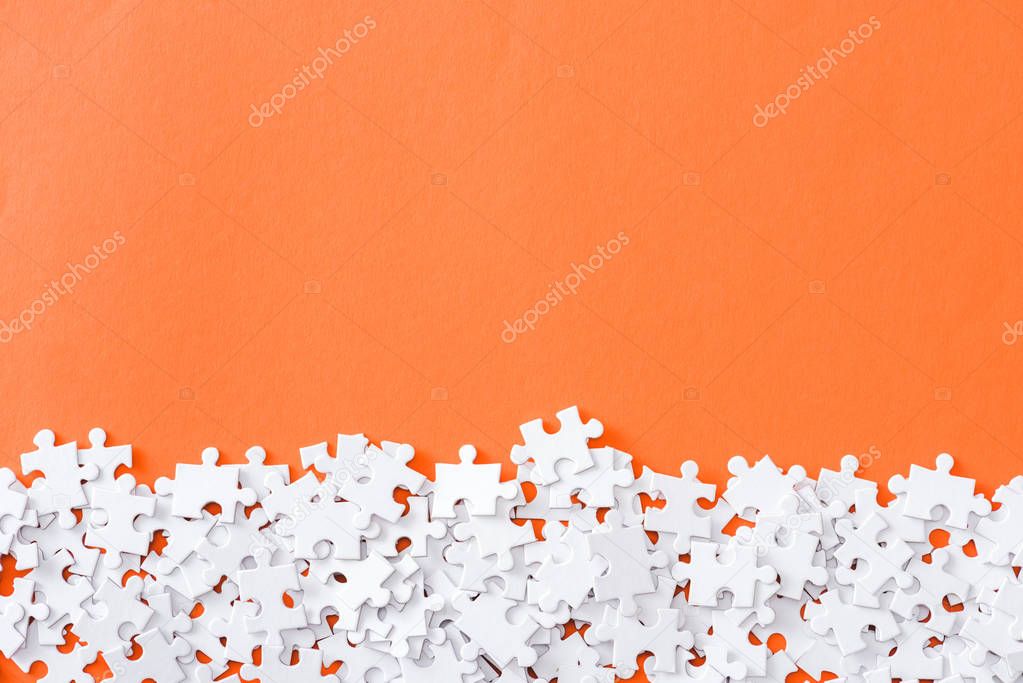 top view of unfinished white puzzle pieces isolated on orange with copy space