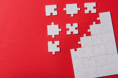 top view of connected and separate jigsaw puzzle pieces isolated on red  clipart