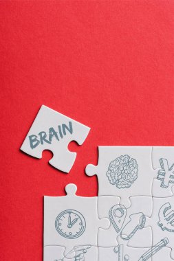 top view of unfinished white puzzles near separate piece with brain lettering isolated on red  clipart
