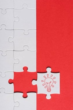 top view of incomplete jigsaw near white puzzle piece with light bulb isolated on red clipart