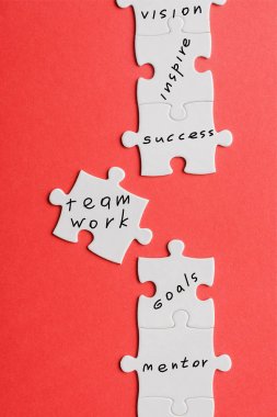 top view of white connected jigsaw near puzzle piece with words isolated on red  clipart