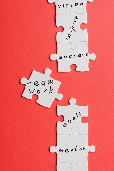 top view of white connected jigsaw near puzzle piece with words isolated on red 