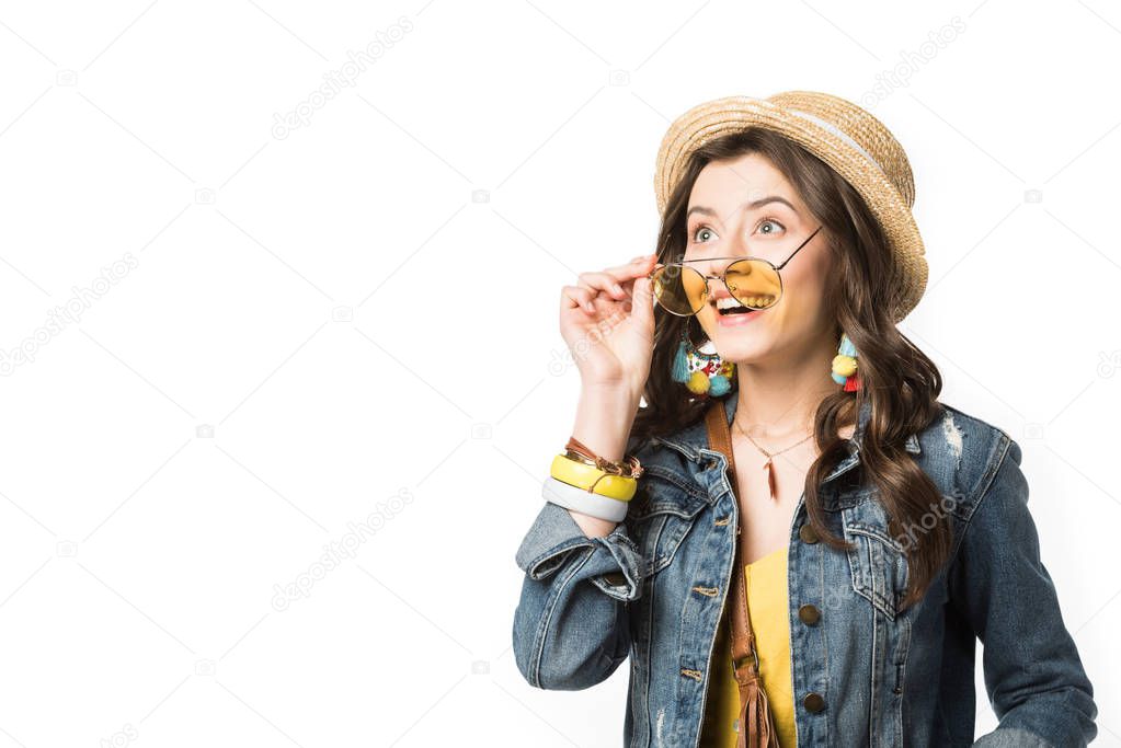 excited boho girl wearing bracelets touching sunglasses with smile isolated on white