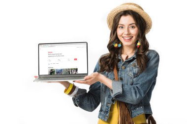 Kiev, Ukrayna - 4 Şubat 2019: beyaz izole ekranda airbnb web sitesi ile dizüstü bilgisayar tutan hasır şapka gülümseyen hippi kız